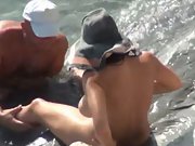 Mature couple fooling around in the surf giving each other oral sex